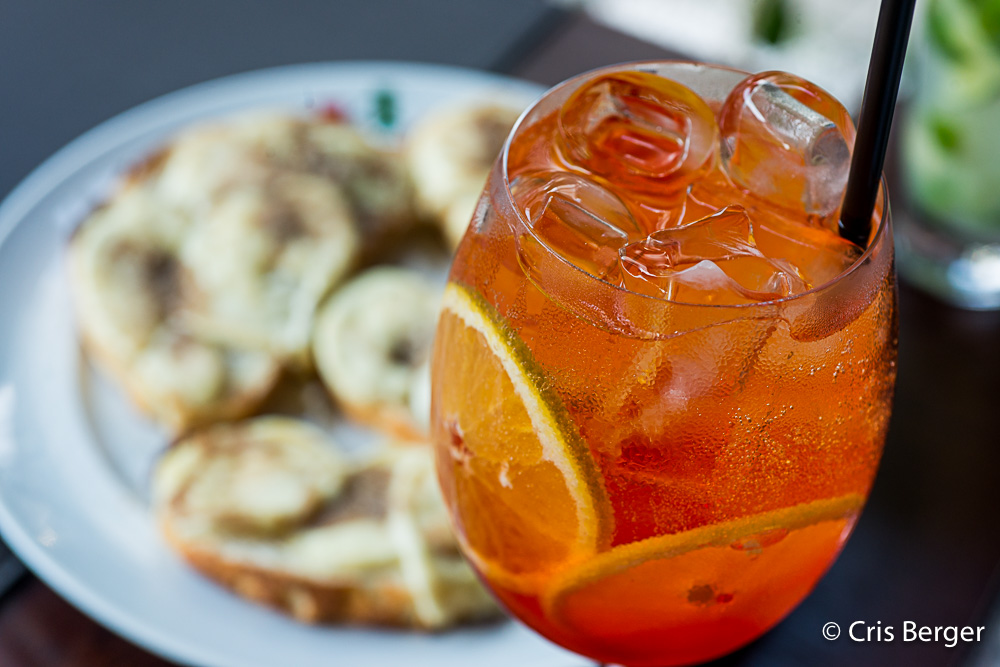 Spazio Gastronômico é pet friendly aperol spritz com comida ao fundo
