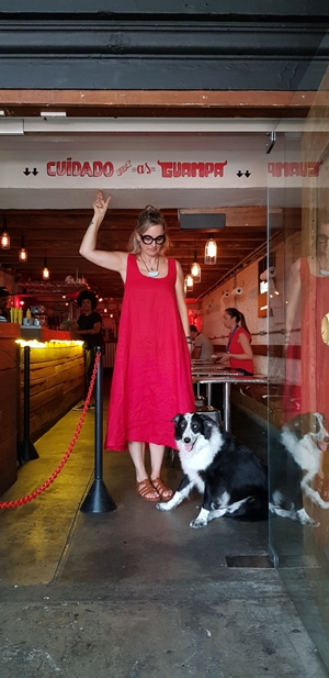 mulher de vestido vermelho e cachorro na entrada de restaurante
